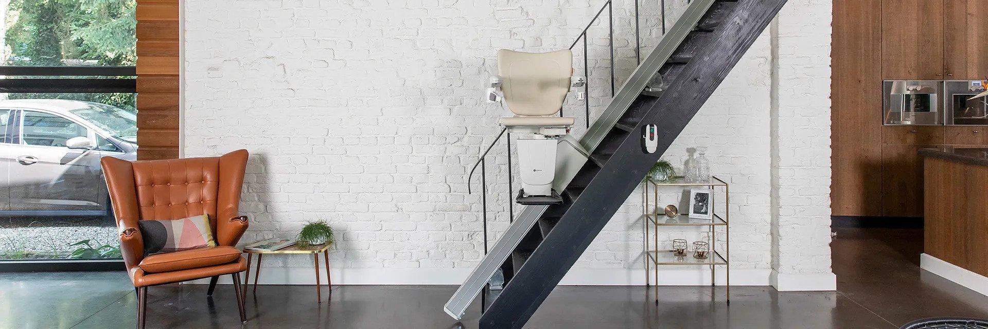 Monte-escalier installé sur un escalier droit dans un intérieur moderne avec fauteuil en cuir et décoration minimaliste.